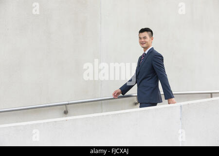 Side view of a happy Asian Businessman walking on city street. Stock Photo