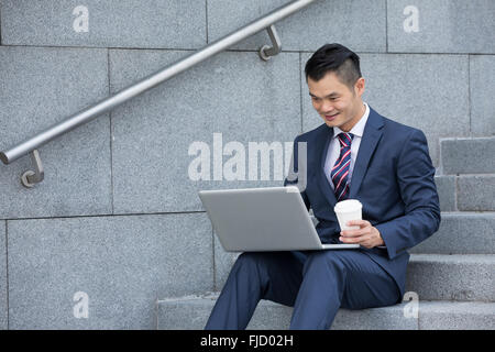 Chinese/Asian business Man using his laptop in a cafe Stock Photo