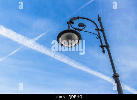 A retro-style street light with blue sky and chemtrails on background. Stock Photo