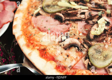 Tasty pizza slice with ham, mushrooms and cucumbers. Shallow depth of field Stock Photo