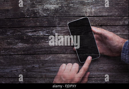 Male hands in shirt using smartphone with large blank touchscreen on dark rustic wood double exposure. With copy space. Stock Photo