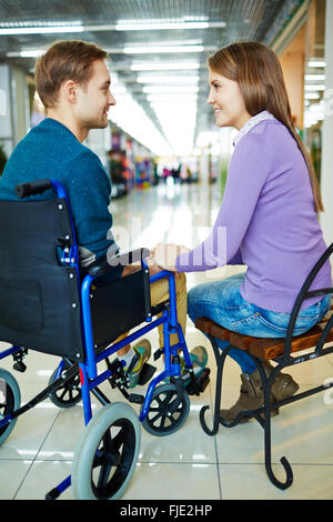 Young woman with her boyfriend on wheelchair communicating with each other Stock Photo