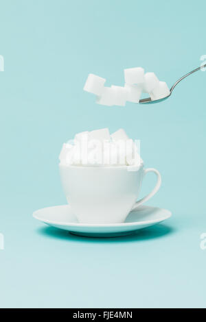 Adding an excessive amount of sugar in a tea cup. Stock Photo