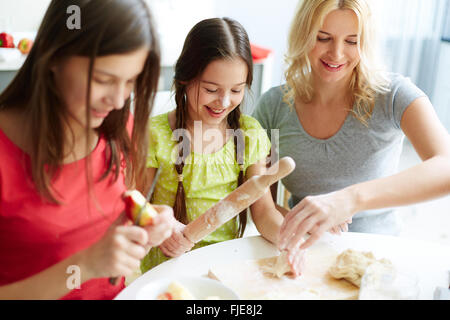 Two daughters helping their mother in the kitchen Stock Photo