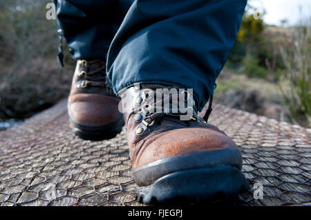 Close up, ground level perspective, of a persons feet wearing walking boots, stepping toward the camera. Stock Photo