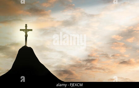 Silhouette Jesus and the cross over sunset on mountain top Stock Photo
