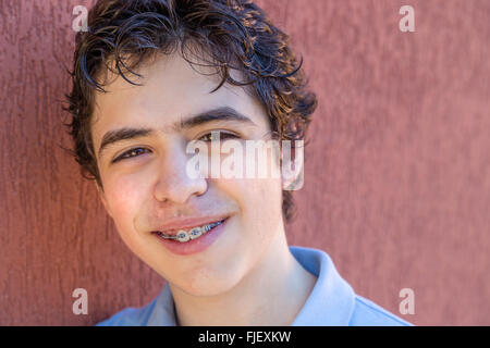 boy smiles leaning against a grunge red wall Stock Photo