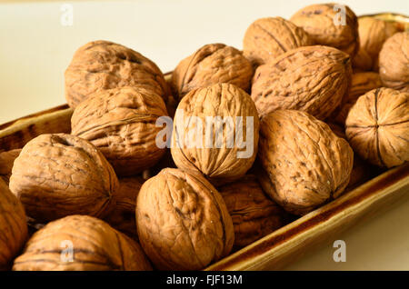 Walnuts in shells in a porcelain container. Stock Photo