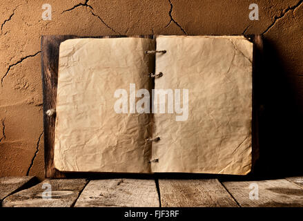 Opened old book on table near clay wall Stock Photo