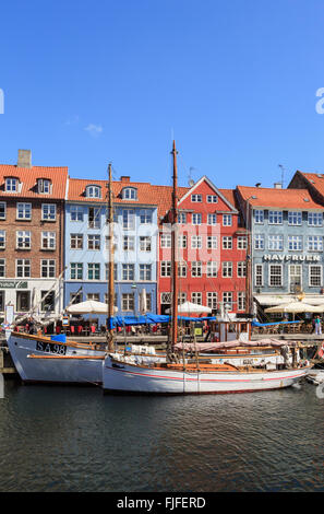 Old wooden boats moored on canal quay with colourful buildings on the waterfront in Nyhavn Copenhagen Denmark Scandinavia Stock Photo