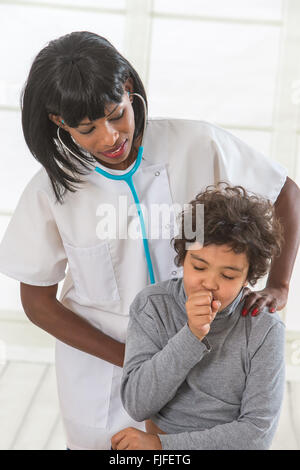 Health worker listens to lungs of young patient in exam room Stock Photo