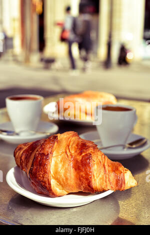 closeup of a table in the terrace of a cafe set for breakfast, with some cups of coffee, a croissant and a spanish omelette sand Stock Photo