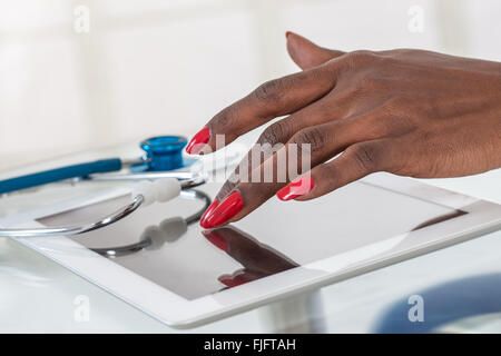 Close-up Of Doctor hans  on  Digital Tablet At Desk with stethoscope Stock Photo