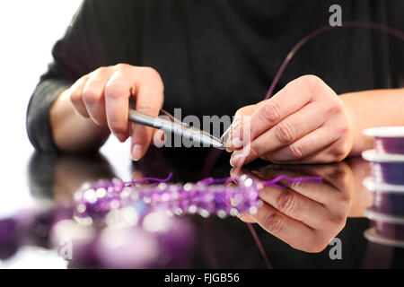 Amethyst, a beautiful purple necklace. Threading beads, jewelry workshop. Creating jewelry. Stock Photo