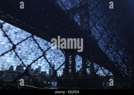 Distorted industrial view of Manhattan Bridge waterfront New York City photographed through a wire fence Stock Photo