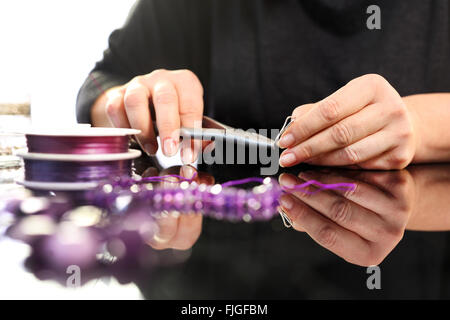 Amethyst, a beautiful purple necklace. Threading beads, jewelry workshop. Creating jewelry. Stock Photo