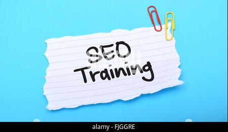 SEO Training written on paper with blue background. Stock Photo