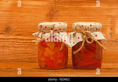 Two glass jars of homemade quince jam with textile top decoration at unpainted brown vintage wood Stock Photo