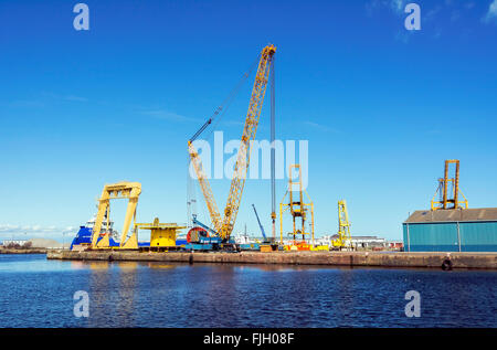 Heavy lifting cranes on the quayside at Leith Docks, Edinburgh. The offshore supply ship 'Sea Falcon' is in the background. Stock Photo