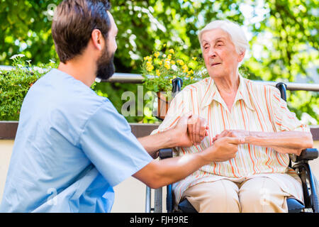 Geriatric nurse holding hand of old woman in rest home Stock Photo