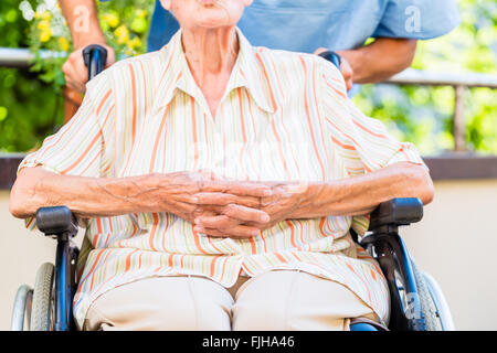 Geriatric nurse pushing senior lady in wheel chair thru home Stock Photo