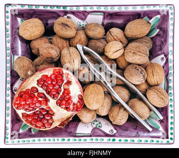 Tray with walnuts, nutcracker and slice of pomegranate, taken from above. Stock Photo