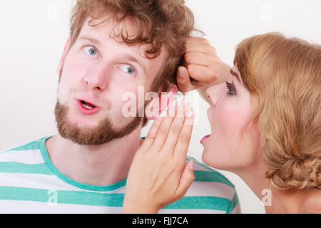 Closeup woman telling an astonished surprised man some secrets, couple talking Stock Photo