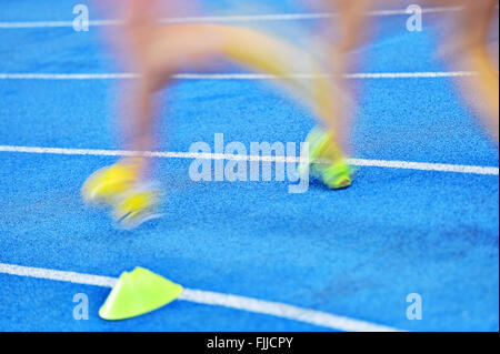 Blurred athletes by a slow camera shutter speed competing on blue sprint track Stock Photo