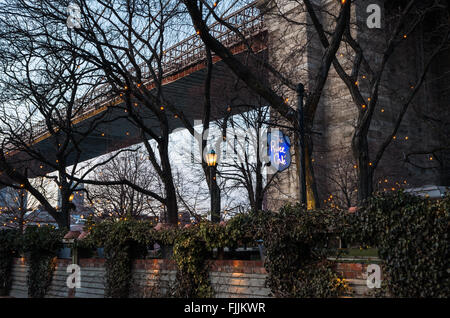 The garden on the River Cafe in DUMBO, Brooklyn sits underneath the Brooklyn Bridge. Stock Photo
