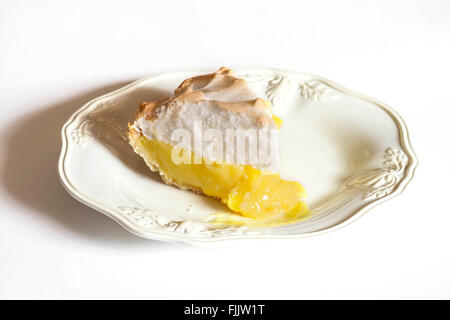 A slice of lemon meringue cream pie on a white dessert plate, cutout. Stock Photo