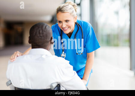 pretty female doctor comforting disabled patient in wheelchair Stock Photo