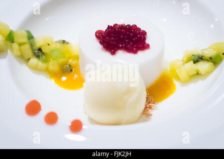 An exquisite coconut panna cotta dessert with hibiscus syrup pearls, pineapple sorbet, blood orange gel, pineapple, and kiwi. Stock Photo