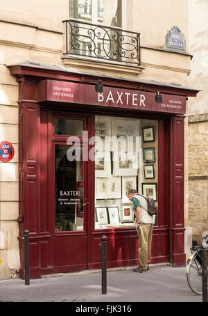 Man looking at antique prints in shop window on the Rue du Dragon in the trendy Saint Germain district, Paris, France Stock Photo