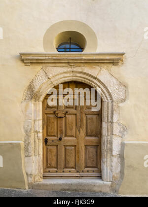 Heavy wooden door in an ancient arched stone doorway in the historic village of Sablet, Vaucluse, Provence, France Stock Photo