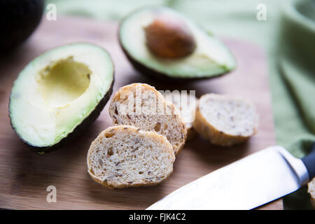 Fresh avocado cut in half and small slices of bread for making avocado toast. Stock Photo
