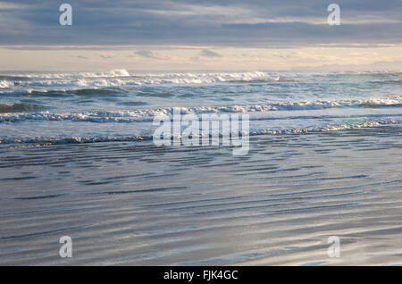 Sunlit waves rolling in from the Bay of Plenty to the beach at Ohope, North Island, New Zealand Stock Photo