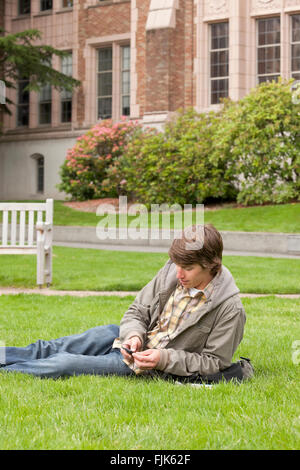 Male college student listening to music or other content with digital audio device on university campus Stock Photo