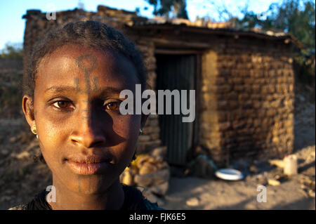 Young woman belonging to the Agaw people. She is standing in front of the house she is renting with two other families. Stock Photo