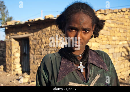 Young woman belonging to the Agaw people. She is standing in front of the house she is renting with two other families. Stock Photo