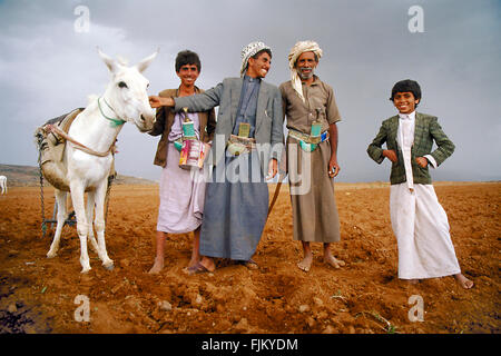 Father and sons together with their donkey posing for the photographer at a farm in Yemen. Stock Photo