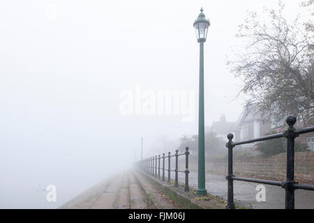 Foggy scene. Old lamp post and railings in fog on a footpath by the River Trent in Autumn. West Bridgford, Nottinghamshire, England, UK Stock Photo