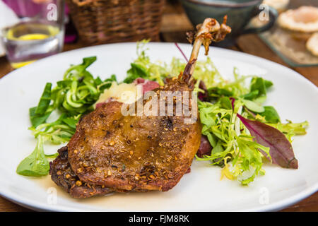 Dish with a roasted duck leg and green salad on a white plate Stock Photo