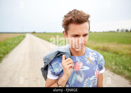 sad young hippie man walking along country road Stock Photo