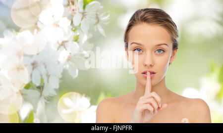 beautiful young woman holding finger on lips Stock Photo