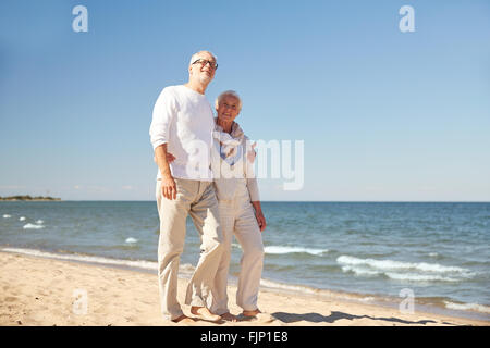 happy senior couple walking along summer beach Stock Photo