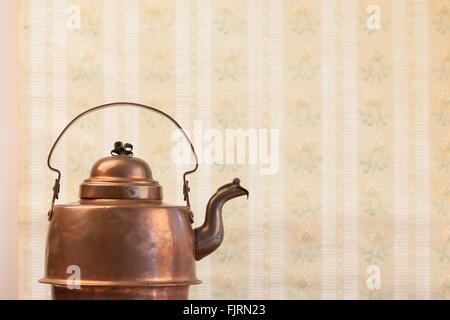antique vintage copper kettle on the background of old wallpaper Stock Photo