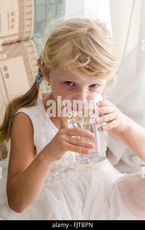 beautiful little blond drinking water from glass Stock Photo