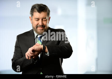 Portrait of Hispanic businessman using smart watch inside office building Stock Photo