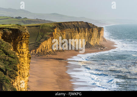 East Cliff at West Bay and Burton Cliff at Burton Bradstock in Dorset glow under winter sunshine in January. Picture Credit: Graham Hunt/Alamy Stock Photo