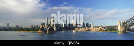 Panoramic view of Sydney skyline with Opera House and Harbour Bridge on right with ferryboat crossing Stock Photo
